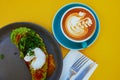 Cup of fresh flat white coffee and delicious toast with avocado and egg Benedict Royalty Free Stock Photo