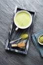 A cup of fresh frothy Matcha green tea decorated with bamboo whisk