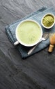 A cup of fresh frothy Matcha green tea decorated with bamboo whisk