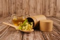 Cup of fresh herbal linden tea, organic herbal infusion with linden flowers on wooden spoon and paper tube for packaging