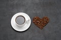 Cup of fresh hot espresso coffee and heart shape made of beans on a dark concrete Royalty Free Stock Photo