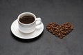 Cup of fresh hot espresso coffee and heart shape made of beans on a dark concrete Royalty Free Stock Photo