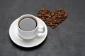 Cup of fresh hot espresso coffee and heart shape made of beans on a dark concrete Royalty Free Stock Photo