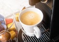 Cup of fresh morning coffee with espresso machine and sunlight on white background with capsules pods Royalty Free Stock Photo