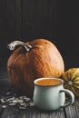 Cup of fresh pumpkin juice, ripe pumpkins and seeds on table