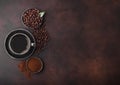 Cup of fresh raw organic coffee with beans and ground powder with cane sugar cubes with coffee tree leaf on brown background.