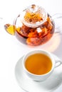 A Cup of fresh tea on a saucer, behind the Tea in a glass teapot with a blooming large flower. Exotic green tea on white Royalty Free Stock Photo