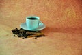 A cup of freshly brewed black coffee on a saucer in a pile of grains and cinnamon on a brown isolated background. Close up shot Royalty Free Stock Photo