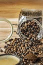 A cup of freshly brewed coffee on a wooden table filled with overturned coffee beans from a tin and a copper meter with ground Royalty Free Stock Photo