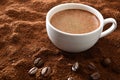 Cup of frothy coffee over ground with beans elevated view Royalty Free Stock Photo