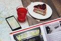 Cup of fruit-drink near map and smartphone with magazine on the table. Top point of view Royalty Free Stock Photo