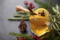 Cup of fruit tea with Apple and lemon, cinnamon, star anise, fir branches, rosemary on a black background, cone, red berries Royalty Free Stock Photo