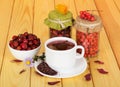 Cup fruit tea, jars with berries mountain ash and rosehip. Royalty Free Stock Photo