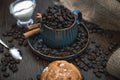 Cup full of coffee beans with bun, milk and canvas on brown table Royalty Free Stock Photo