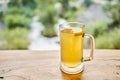 Cup of ginger root tea with lemon, honey and mint on a wooden table and High-mountain river in the background. Walk in