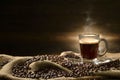 Cup glass of coffee with smoke and coffee beans on burlap sack on old wooden background Royalty Free Stock Photo