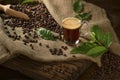 Cup glass of coffee with smoke and coffee beans on burlap sack on old wooden background Royalty Free Stock Photo