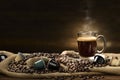 Cup glass of coffee with smoke and coffee beans and coffee capsules on burlap sack on old wooden background Royalty Free Stock Photo