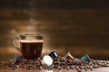 Cup glass of coffee with smoke and coffee beans and coffee capsule on old wooden background Royalty Free Stock Photo