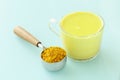 Cup of golden milk and a measuring cup with turmeric powder