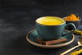 Cup of golden turmeric latte milk on dark. Close up