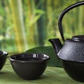 Cup with green tea with black china kettle on nature blur background. Close up. Royalty Free Stock Photo