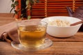 Cooked brown rice in white bowl with chopsticks and cup of green tea on the wooden background. Royalty Free Stock Photo