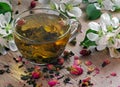 Cup of green tea with dry rose petals and apple tree flowers on a wooden table. top view. copy space Royalty Free Stock Photo
