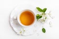 Cup of green tea on figured saucer with white apple tree flowers on white background. Top view. Royalty Free Stock Photo