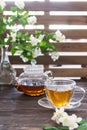 Cup of green tea with jasmine flowers and tea pot on wooden background. Copy space Royalty Free Stock Photo