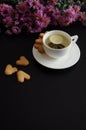 A cup of green tea with sweets and purple flowers on a black background. Royalty Free Stock Photo