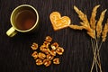 A Cup of green tea on the table with dry spikelets and walnuts on a dark background Royalty Free Stock Photo