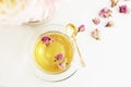A cup of healthy herbal tea with dried roses. Beautiful fresh flowers on light marble table, top view. Pink bouquet on a female wo