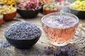 Cup of healthy lavender tea and dry lavender flowers. Healthy lavender tea poured into glass cup. Bowls of dry medicinal herbs.