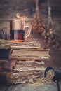 Cup of healthy tea or herbal tincture on stack of old books, mortar of daisy herbs. Royalty Free Stock Photo