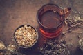 Cup of healthy tea, rustic mortar of daisy herbs, dried thyme on table. Royalty Free Stock Photo