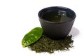 Cup and heap of green shincha tea with leaf.