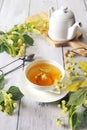 Cup of herbal linden tea with linden flowers and teapot Royalty Free Stock Photo