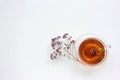 Cup of herbal oregano tea with dry marjoram flowers on white table background with copy space. Top view.