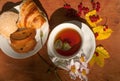 A cup of herbal tea, a plate of fresh pastry, yellow autumn leaves, ripe red currants and garden flowers on a wooden surface Royalty Free Stock Photo