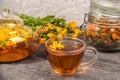 Cup of herbal tea, transparent teapot and marigold flowers on wood background. Calendula Tea Benefits Your Health