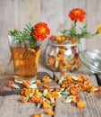 A cup of herbal tea and a transparent teapot with marigold flowers on a wooden background.Marigold tea benefits your health. Royalty Free Stock Photo