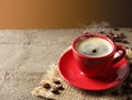 Cup of hot aromatic coffee and roasted beans on wooden table against brown background. Space for text Royalty Free Stock Photo