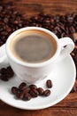 Cup of hot aromatic coffee and roasted beans on wooden table, closeup Royalty Free Stock Photo