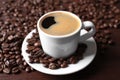 Cup of hot aromatic coffee and roasted beans on wooden table, closeup Royalty Free Stock Photo