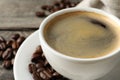 Cup of hot aromatic coffee and roasted beans on wooden table, closeup. Space for text Royalty Free Stock Photo