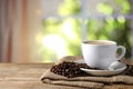 Cup of hot aromatic coffee and roasted beans on wooden table indoors, space for text Royalty Free Stock Photo