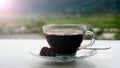 A cup of hot black coffee with brown sugar on plate on white table and blur green nature outdoor background. Morning coffee Royalty Free Stock Photo