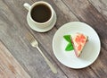 A cup of hot black coffee, a fork and a plate with a piece of red velvet cake decorated with mint leaves on a light wooden table Royalty Free Stock Photo
