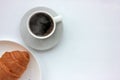 Cup of hot blak coffee with steam and croissant on white background. Top view, copy space. Morning espresso on table.